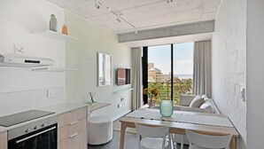 Una cucina moderna con forno integrato, mobili bianchi e un'area pranzo con tavolo e sedie.
