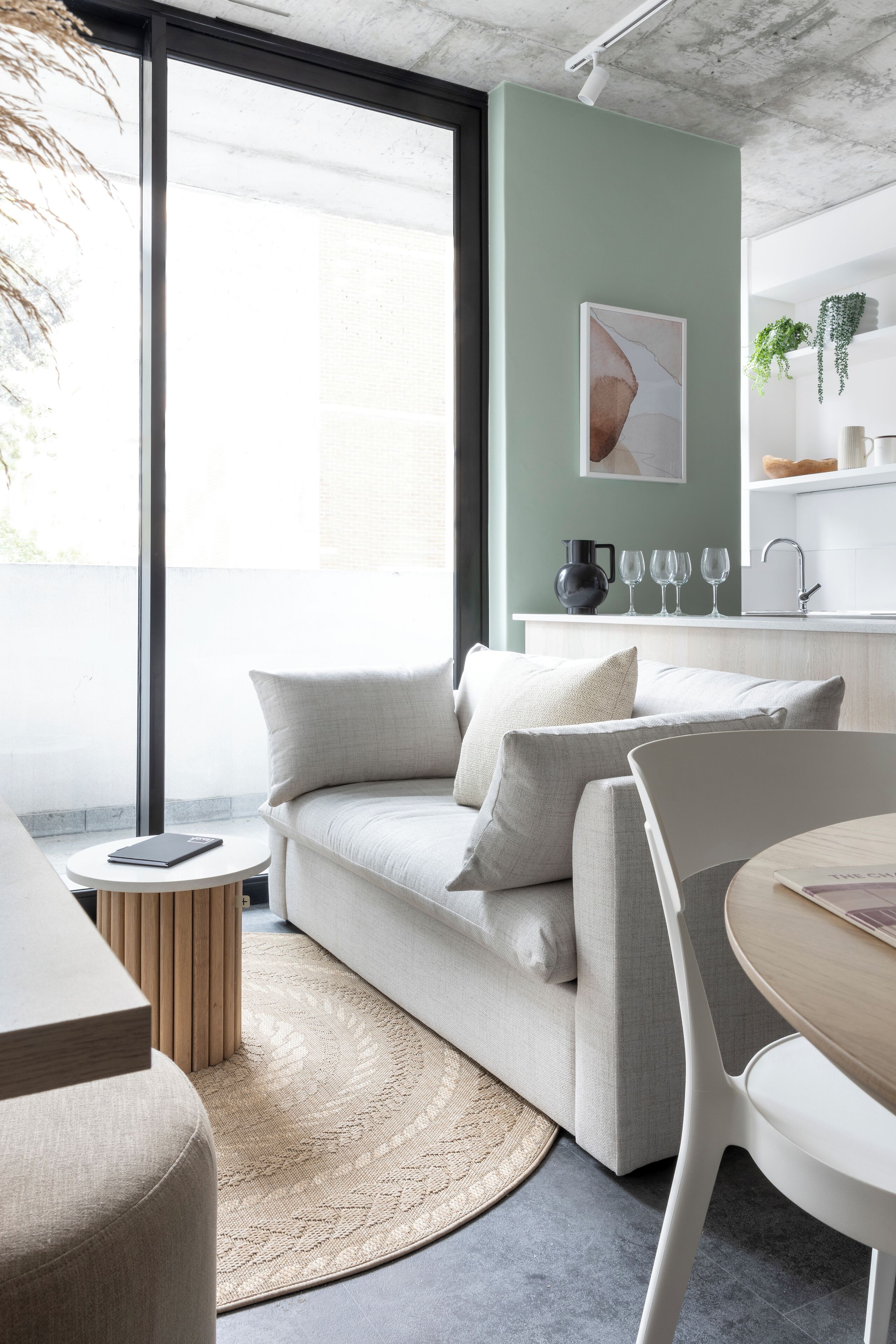 A modern living space with a sofa, a round table, and a kitchen area with a sink and countertop.