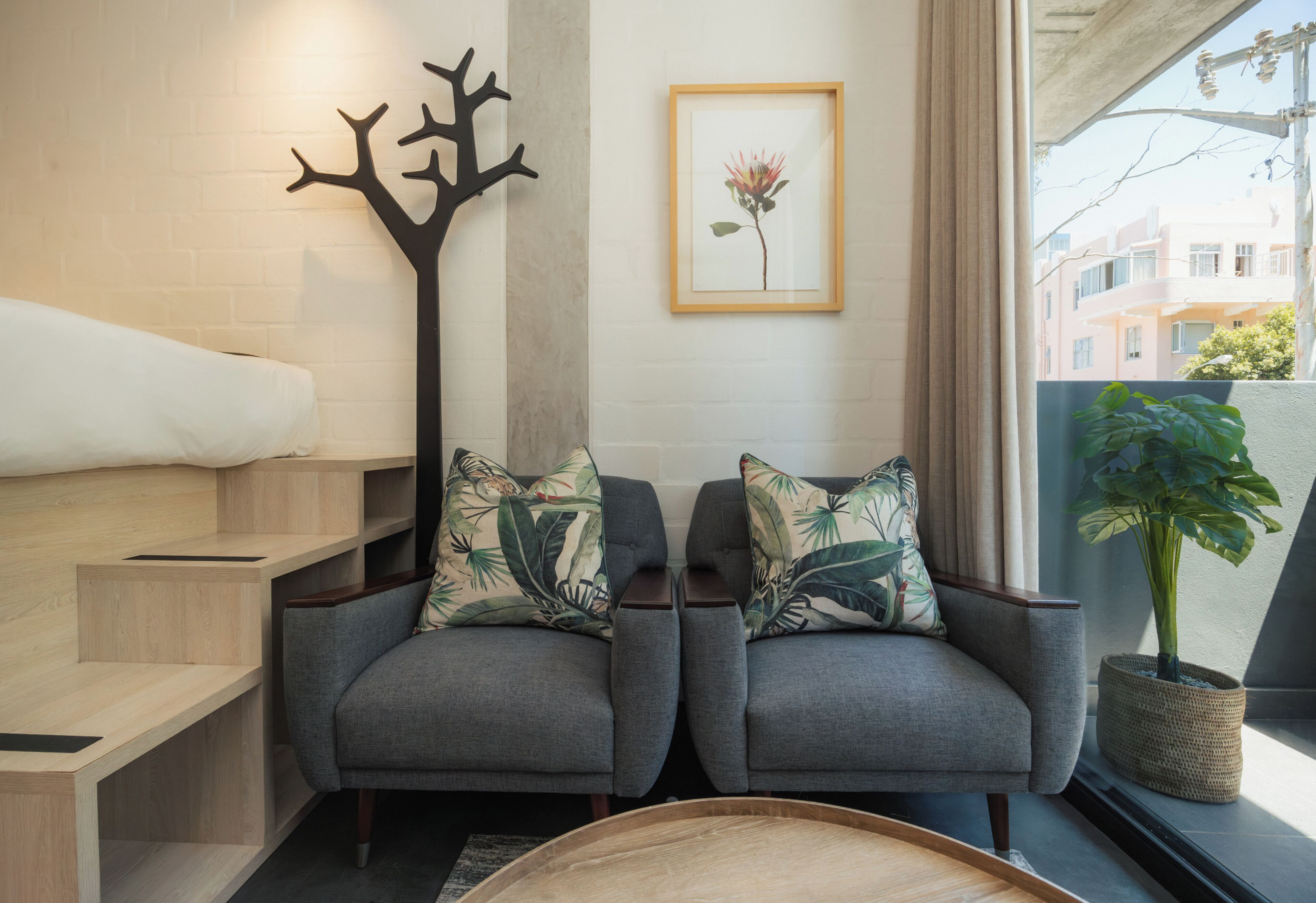 A modern living room with a sofa set, a decorative tree sculpture, and a framed artwork on the wall.