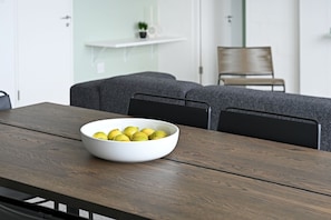 A dining table with a white bowl of lemons.