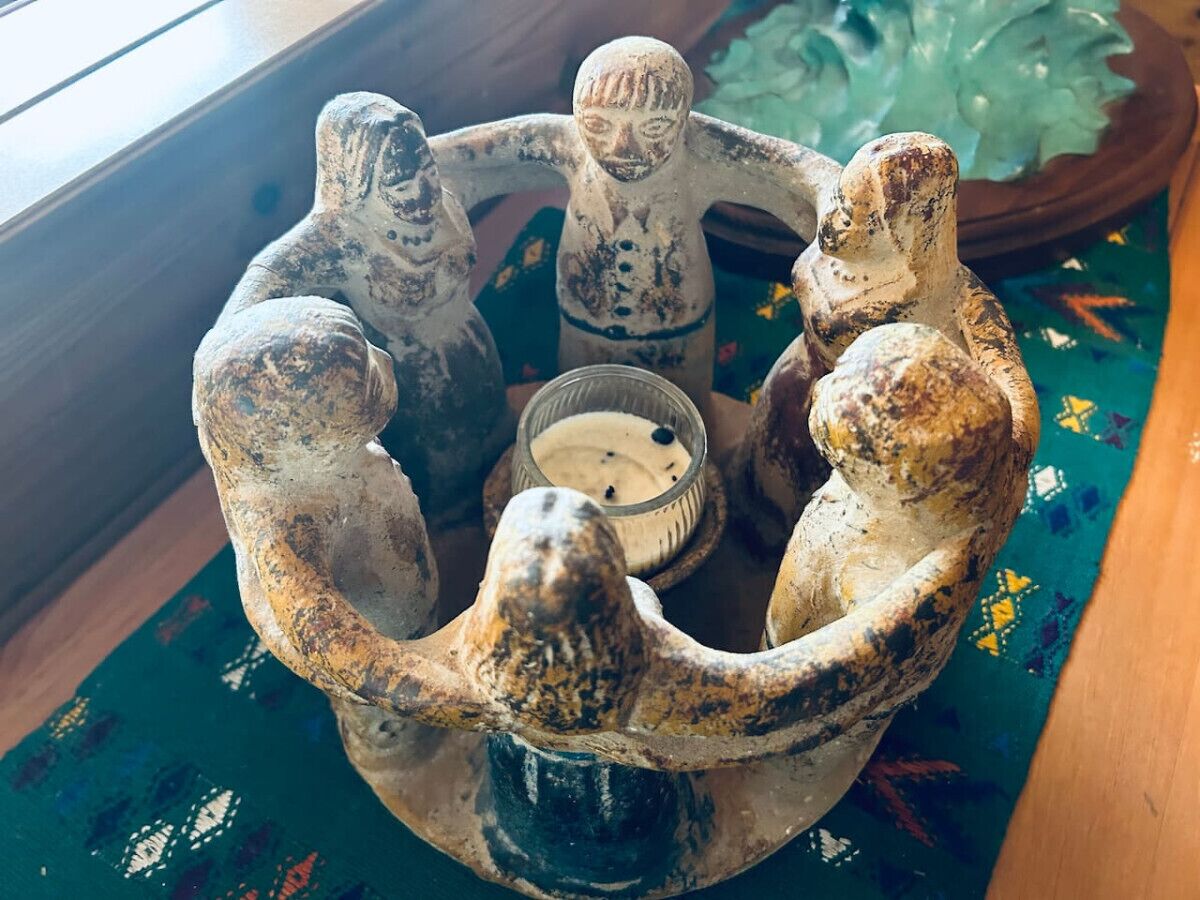 A rustic, circular wooden table with four animal figurines and a candle holder.