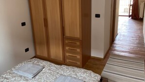 Una camera da letto con un letto, un armadio in legno e vista su un balcone.