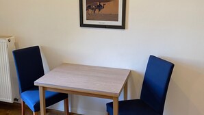 Una stanza con un tavolo e due sedie, un quadro appeso al muro e un termosifone.