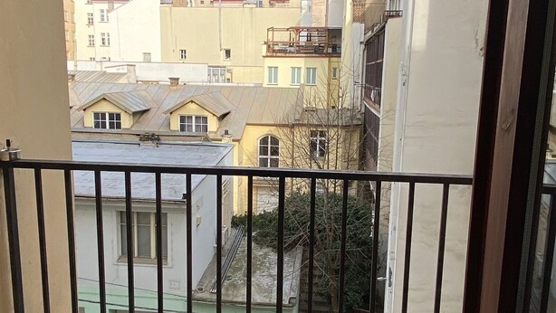 Un balcone con vista sugli edifici vicini, una sedia e una ringhiera.