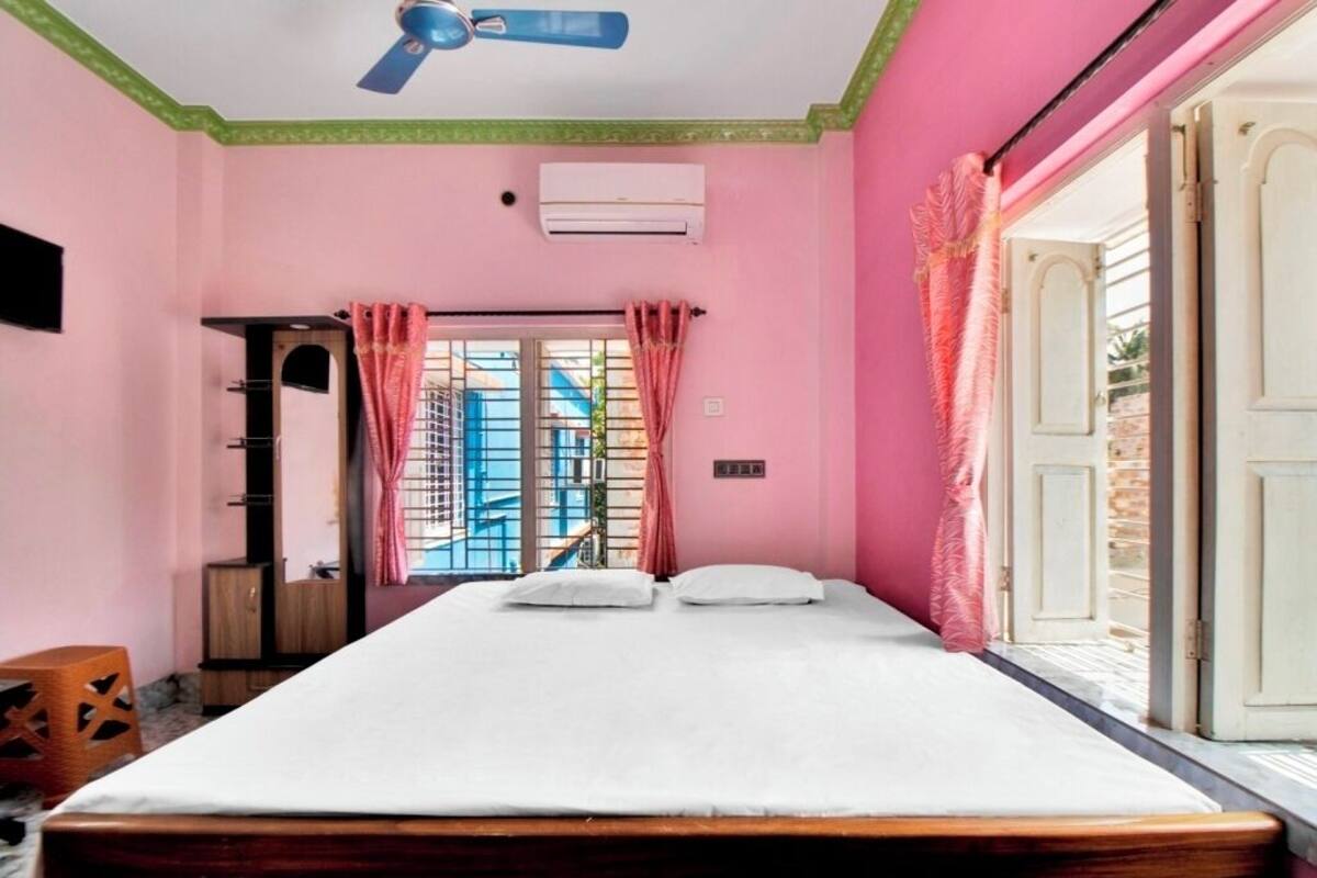 A bedroom with a bed, a ceiling fan, an air conditioning unit, and a view through a door.