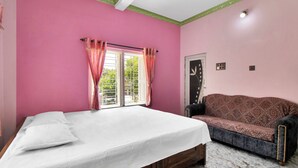 Una camera da letto con un letto, un divano e una finestra con tende.