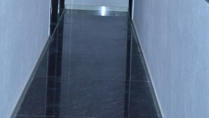 A narrow, polished corridor with a modern ceiling design and a door at the end. - Girdhar Sanwaria Palace (Danta Ramgarh)
