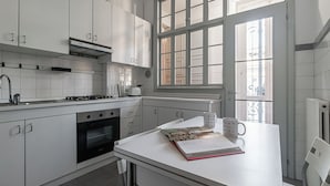 A modern kitchen with white cabinetry, a built-in oven, a stove, and a window with a view of the outside. - Italianway Easy - Bligny 26 (Milan)