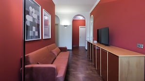 A hallway with a wooden bench, a television on a stand, and framed pictures on the wall. - Italianway Easy - Bligny 26 (Milan)