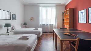 A hotel room with two beds, a dining table, and a bookshelf. - Italianway Easy - Bligny 26 (Milan)