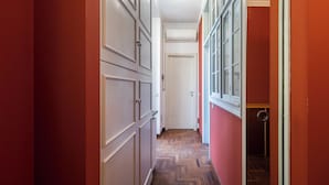 A hallway with a herringbone patterned floor, a door at the end, and a window with white frames. - Italianway Easy - Bligny 26 (Milan)