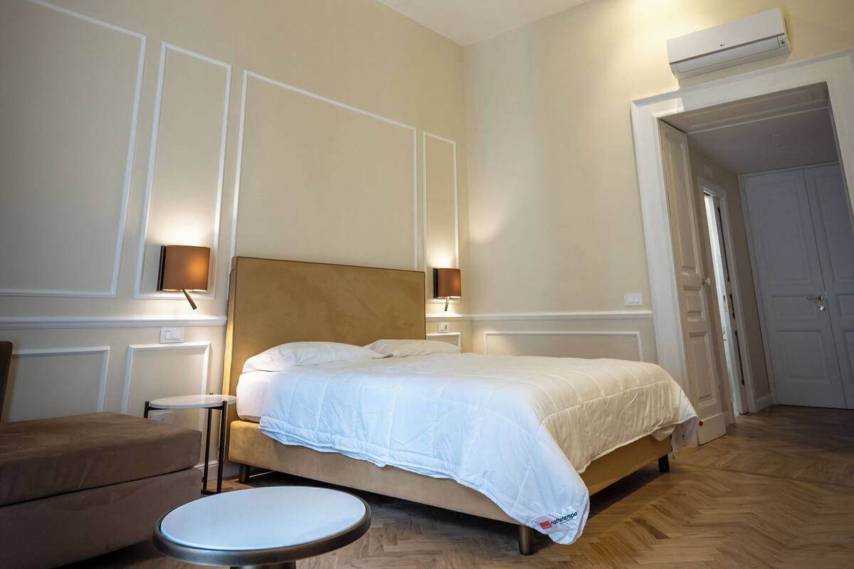 Une chambre d’hôtel avec un grand lit, une petite table ronde et un plafond décoratif.