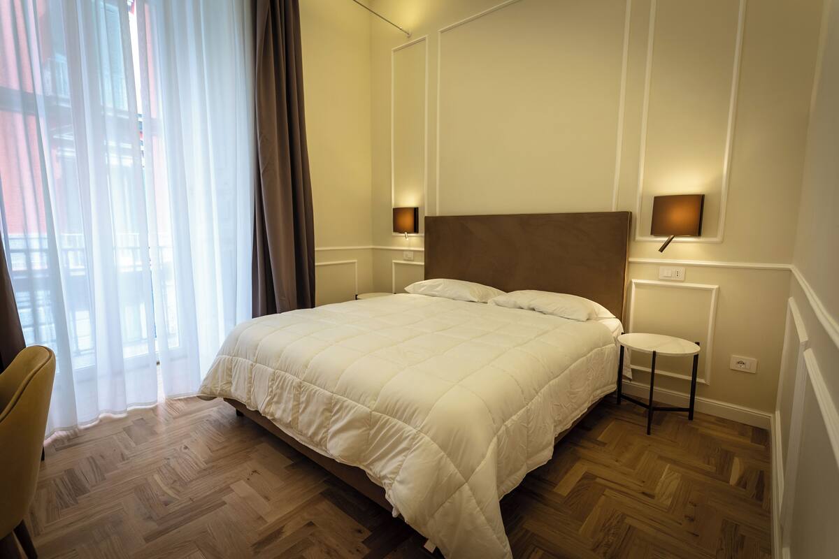 Une chambre d’hôtel avec un grand lit, une chaise et une petite table.