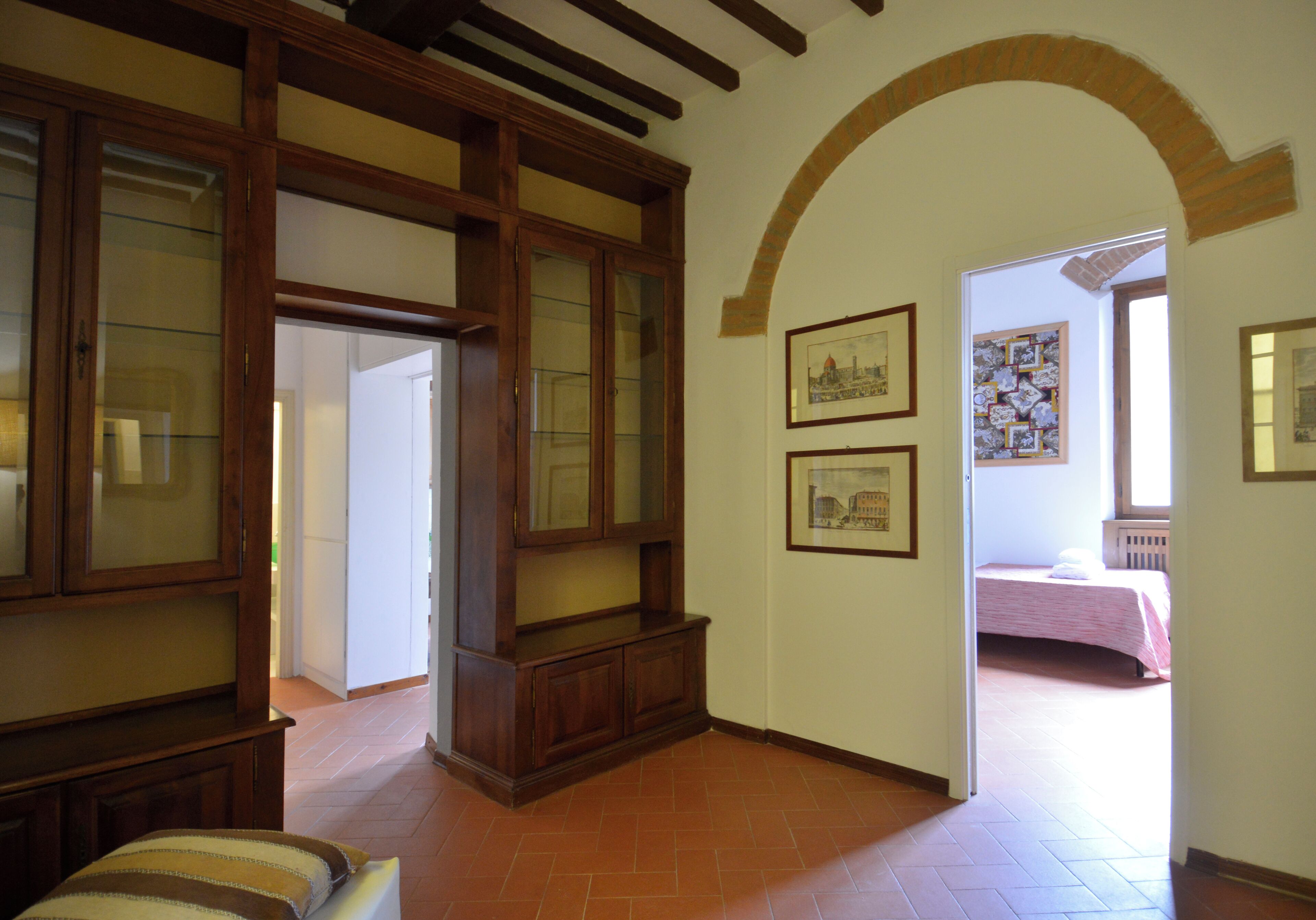 Un couloir avec une armoire en bois, un lit à l’arrière-plan et une porte donnant sur une autre pièce.