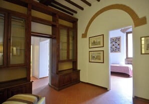 Un corridoio con un armadietto in legno, un letto sullo sfondo e una porta che dà su un'altra stanza.