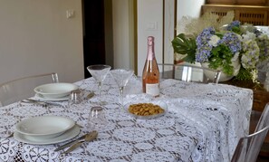 A dining table set with white plates, cutlery, a glass, a bottle of rose wine, and a bowl of snacks. - HORTUS FLORENS, 3 minutes from the Brancacci Chapel, elegant apartment for 4–6 guests. (Firenze)