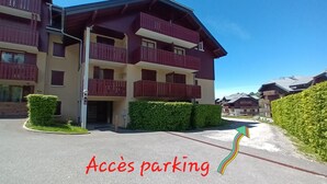Un hotel de varios pisos con balcones y un estacionamiento.