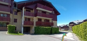 A multi-story hotel with balconies and a parking area.