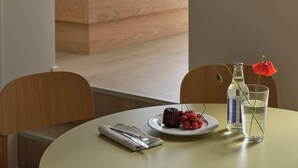 Una habitación de hotel con una cama, una mesa de comedor con un plato de comida, un vaso de agua y una botella.