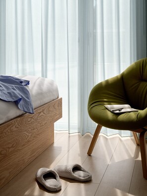 A bedroom with a wooden bed, a green chair, and slippers on the floor. - Studio Apartment for 2 with Terrace (København)