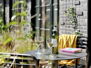 A table with two wine glasses and a bottle of wine, a book titled "Woman Destroyed De Beauvoir," and a yellow cloth on a chair. - Studio Apartment for 2 with Terrace (København)