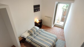 A small, compact bedroom with a bed, bedside table, and a radiator. - Casa in Collina - nel Borgo di Tenaglie (montecchio)