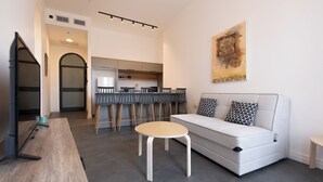 A modern living room with a sofa, a coffee table, and a dining area with chairs. - PORT CITY HAIFA -  Flea Market Luxury (Haifa)