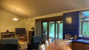 Ein Wohnzimmer mit Esstisch, Stühlen, Fernseher und Bücherregal.