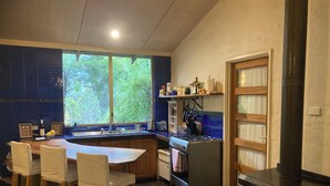 Eine Küche mit einem großen Fenster, einem Herd und einem Kaminofen.
