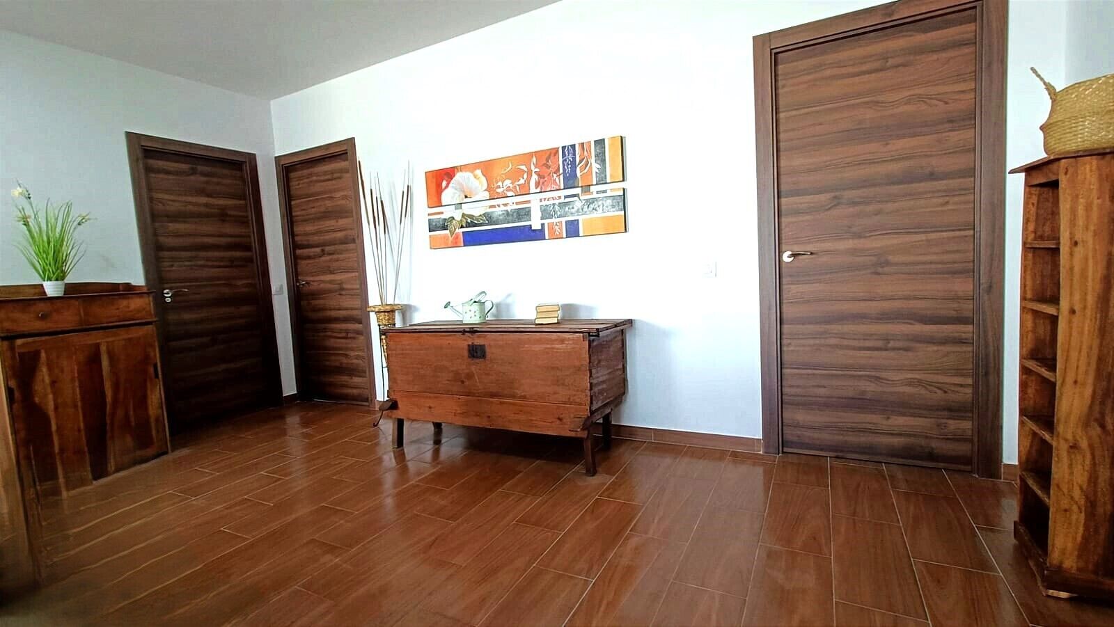 A room with wooden flooring, a wooden dresser, and two wooden doors.