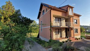 Un edificio a due piani con un balcone, facciata in pietra e vialetto lastricato.
