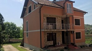 Una casa a due piani con facciata in pietra, un balcone e un giardino.