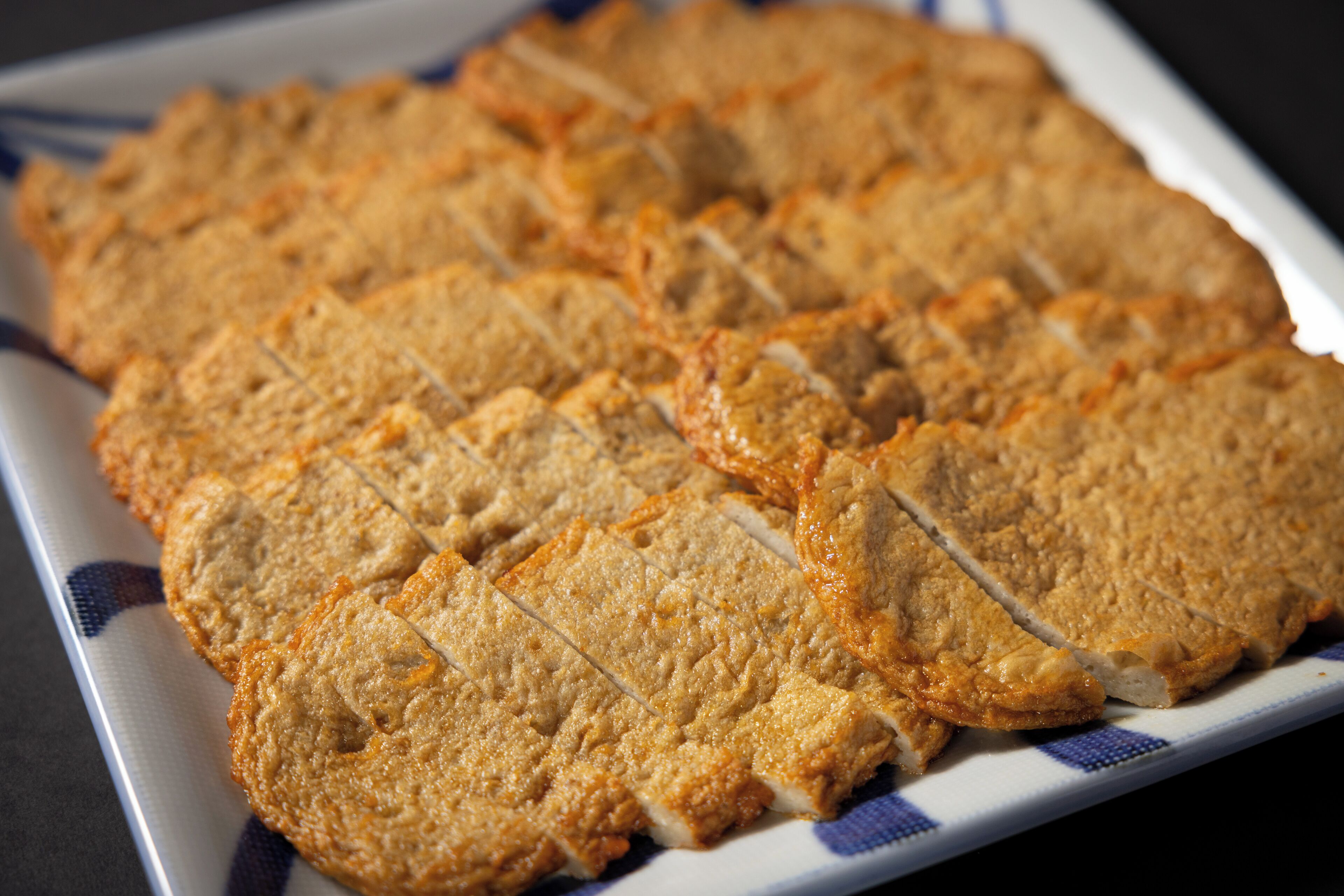 A plate of sliced bread with a golden-brown crust, arranged neatly on a white plate with blue patterns.