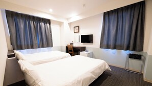 Habitación de hotel con dos camas, un escritorio, una silla, un televisor y una ventana con cortinas.