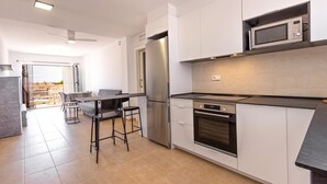 Eine moderne Küche mit Kühlschrank, Mikrowelle, Ofen und einem Essbereich mit Stühlen und Tisch.