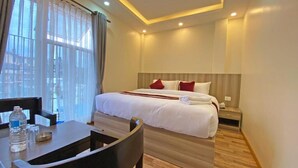 A hotel room with a bed, bedside table, and a desk with chairs. - Hotel Royal Emperor (Kathmandu)