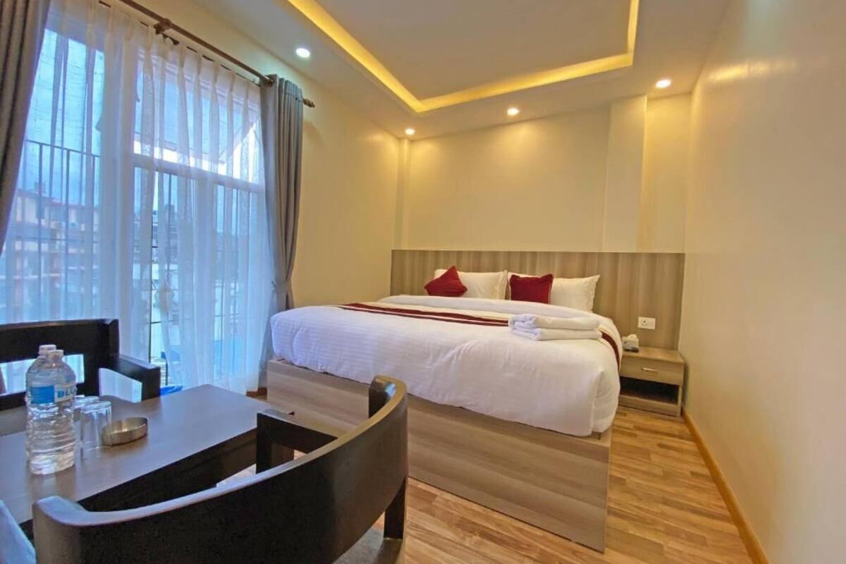 A hotel room with a bed, bedside table, and a desk with chairs.