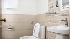 A bathroom with a toilet, sink, and a towel hanging on the wall. - Hotel Royal Emperor (Kathmandu)