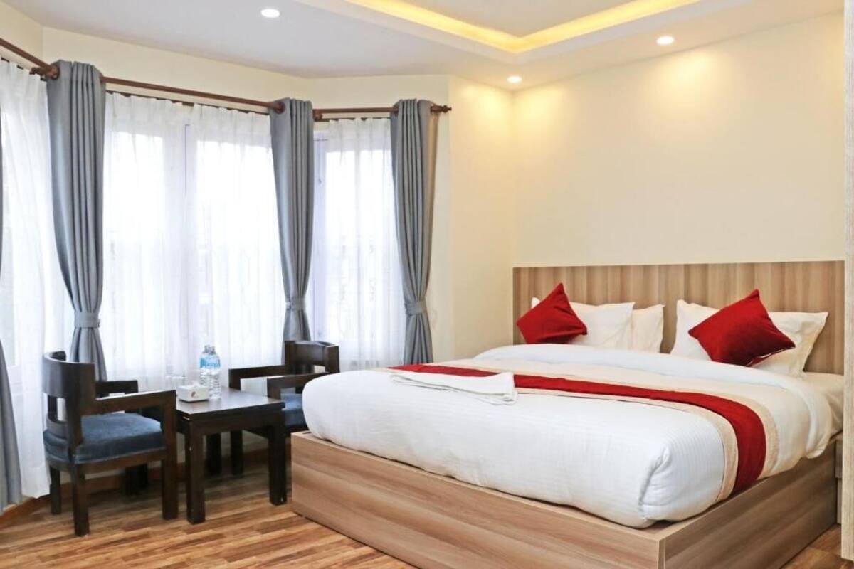 A hotel room with a bed, a desk, and two chairs.