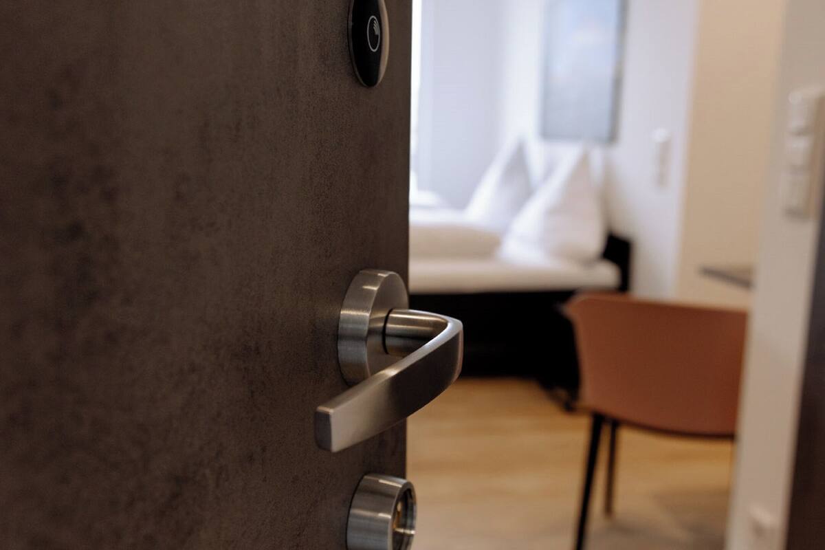 Ein modernes Interieur mit Holzboden, einem Bett mit weißer Bettwäsche und einem braunen Sessel.