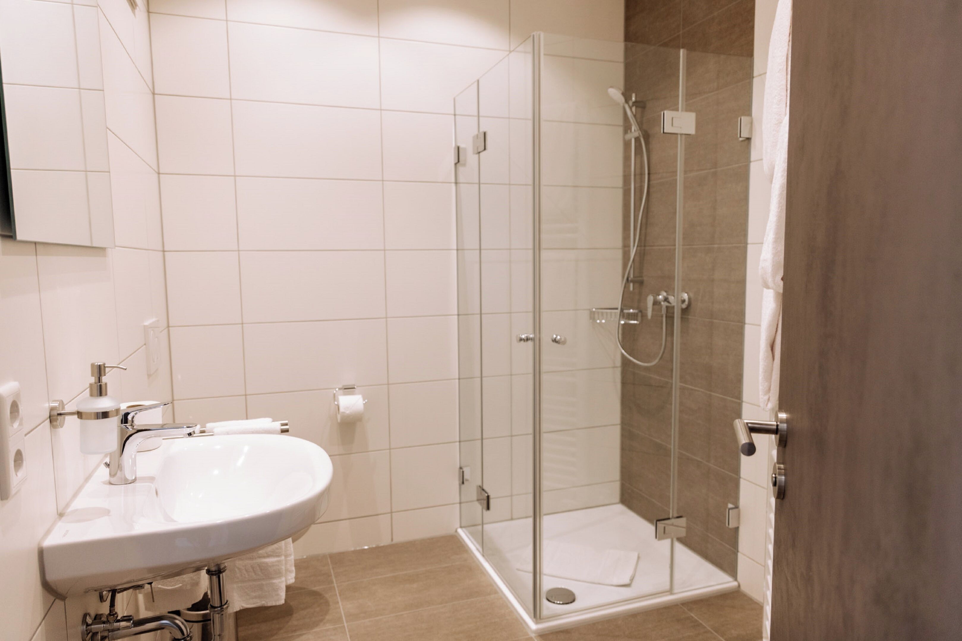 A modern bathroom with a glass-enclosed shower, a white sink, and a toilet.