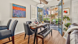A dining area with a wooden table, black upholstered chairs, and a bench. - LV370 Vibrant Downstairs 3BR Legacy Villa Lock-Off (La Quinta)