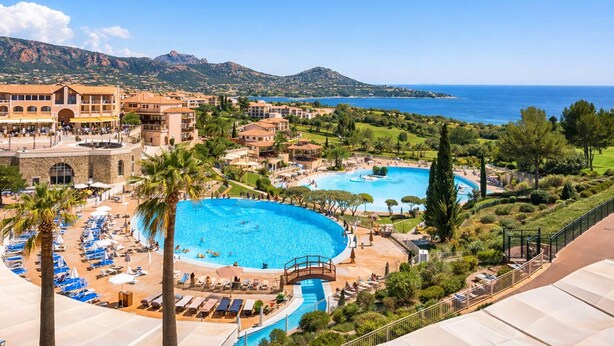 Ett semesterhotell med en stor pool i mitten, flera mindre pooler och utsikt över havet.