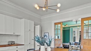 A spacious dining area with a wooden table and chairs, white cabinetry, and a modern chandelier. - Emerald Victorian Patio  4+1 Bd Parking (St. John's)