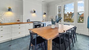 A spacious kitchen with white cabinetry, a wooden dining table, and pendant lighting. - Emerald Victorian Patio  4+1 Bd Parking (St. John's)