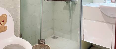 A bathroom with a glass-enclosed shower, a white toilet, and a sink with toiletries.