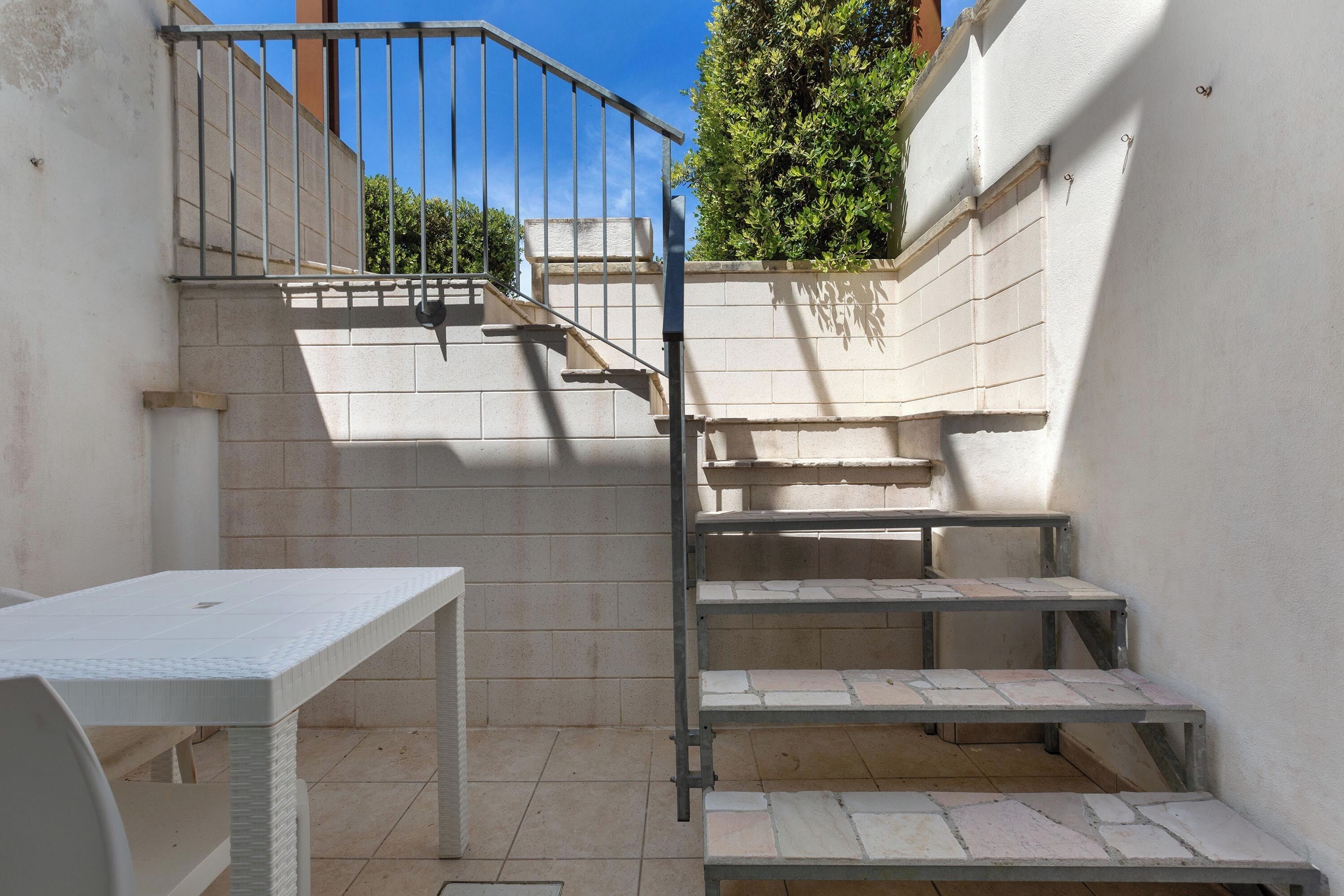 A staircase leading to an upper level, a white table, and a metal railing.