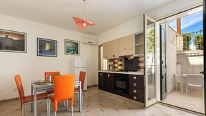 Una cocina moderna con comedor, que cuenta con un amplio ventanal, un salpicadero de colores y una puerta corrediza de vidrio que da a un espacio exterior.