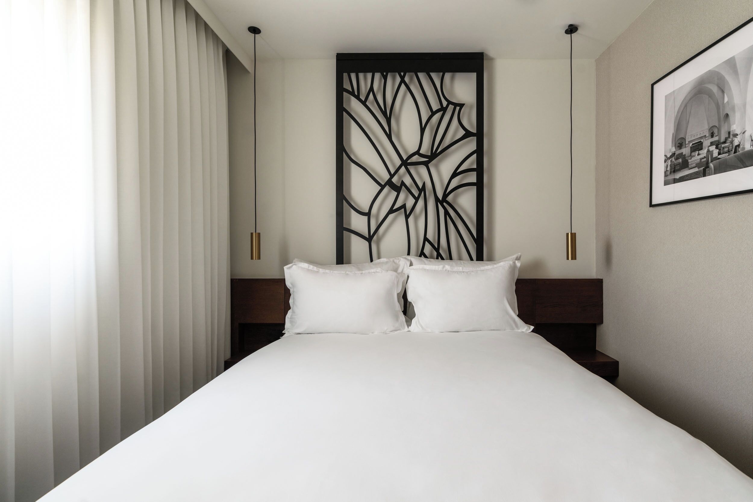 Una camera d'albergo moderna con un letto grande, un pannello decorativo e un quadro appeso al muro.