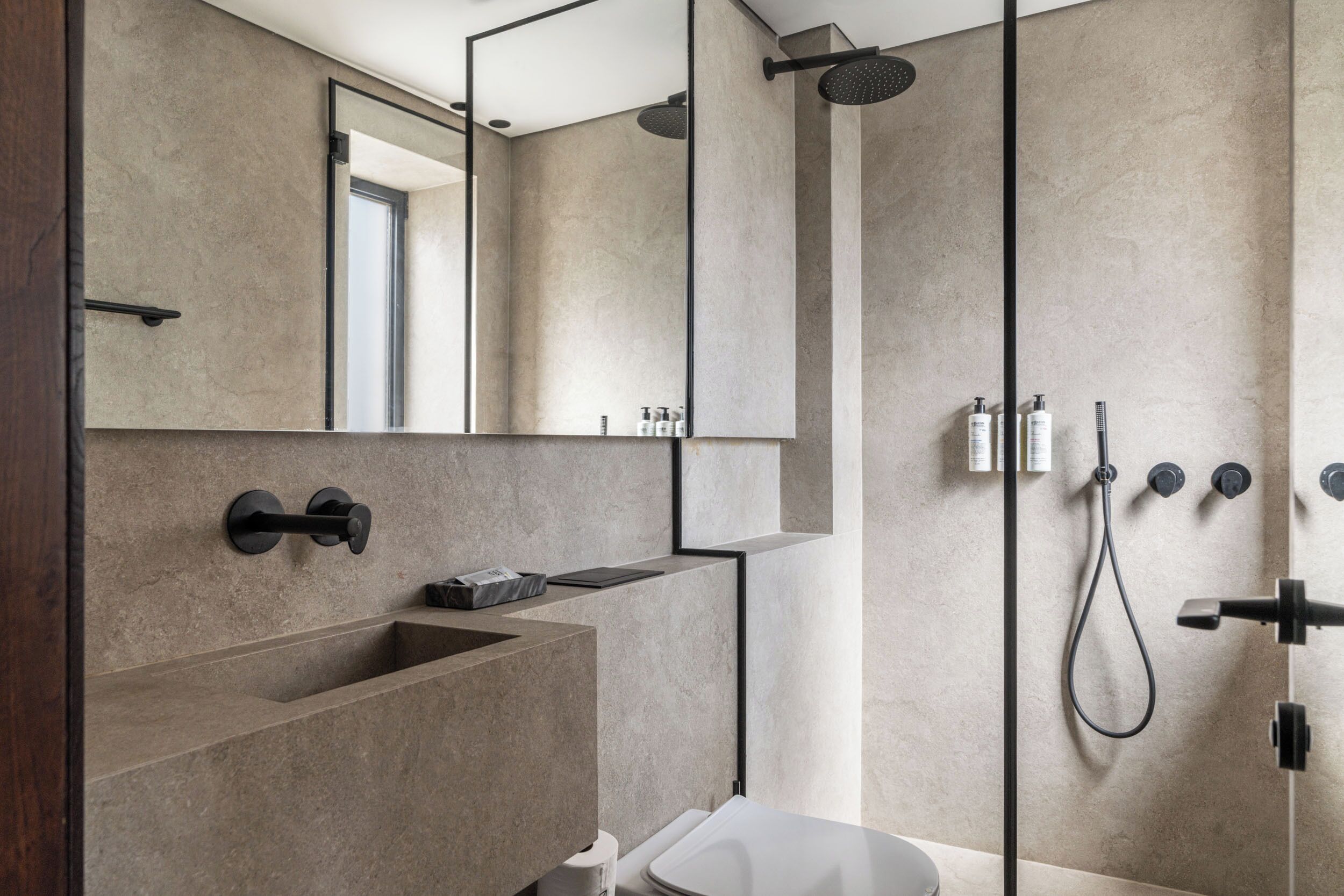 Un bagno moderno con uno specchio grande, un lavabo incassato, un WC e una doccia con comandi multipli.